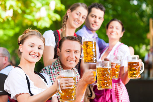 BEine Gruppe junger Leute im Biergarten mit Bierkrügen in Hand – Symbol für deutsche Biertradition